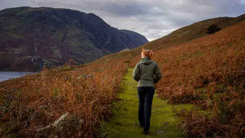 Getty Images Red haired anonymous woman walks outside in rural UK setting