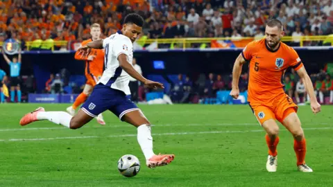 Reuters Watkins aims to kick football past a Netherlands player