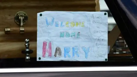 Gleeson Family  A note reading 'Welcome home Harry' in the hearse of a coffin