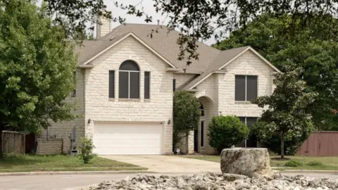 Jack Garland/BBC Large beige suburban house in Austin, Texas, surrounded by trees