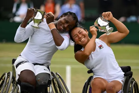 DANIEL KOPATSCH/GETTY IMAGES  Yui Kamiji of Japan and Kgothatso Montjane of South Africa pose with the Ladies' Wheelchair Doubles Trophy following victory against Diede de Groot of the Netherlands and Jiske Griffioen of the Netherlands in the Ladies' Wheelchair Doubles Final during day fourteen of The Championships Wimbledon 2024 at All England Lawn Tennis and Croquet Club on July 14, 2024 in London, England. (Photo by Daniel Kopatsch/Getty Images)