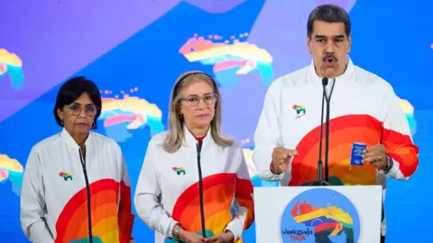 Getty Nicolas Maduro, Venezuela's president, right, speaks to members of the media, next to First Lady Cilia Flores, center, and Delcy Rodriguez, Venezuela's vice president, left, after casting a ballot during a referendum vote in Caracas, Venezuela, on Sunday, Dec. 3, 2023. 