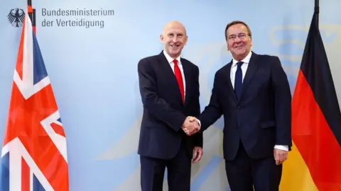 EPA German Defence Minister Boris Pistorius and UK Defence Secretary John Healey shake hands in front of UK and German flags