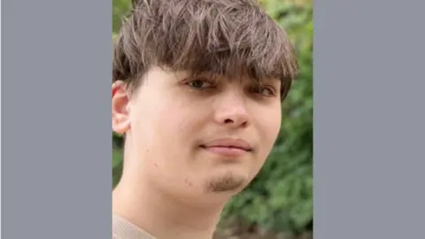 Family photograph Ioan Toma, pictured smiling at the camera. He has dark hair, swept forward towards his eyes. 