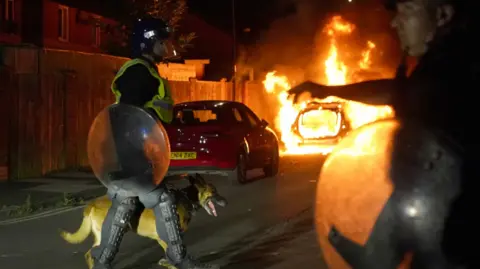 PA Media car burns as officers are deployed on the streets of Hartlepool following a violent protest