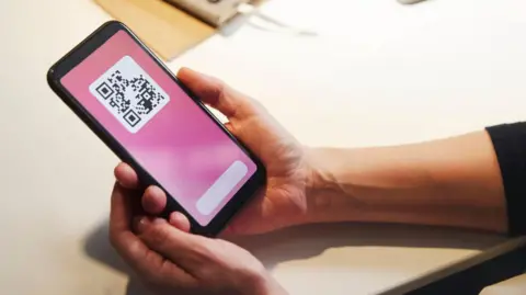 Getty Images A woman looking at a QR code on her phone