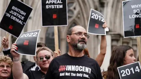 PA Media Andrew Malkinson wearing a t-shirt saying 'innocent' and surrounded by demonstrators holding placards