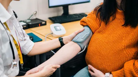 Getty Images Picture of doctor taking a woman's blood pressure