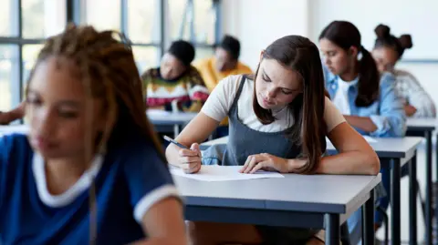 Getty Images Teenage students sitting an exam paper at their individual desks