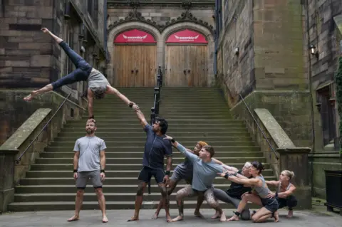 PA Media Acrobats do balancing act in front of some stone steps