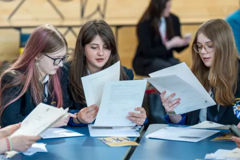 PA Media Three uniformed pupils reading results 