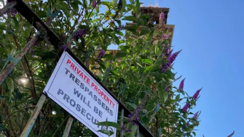 A sign saying trespassers will be prosecuted on railings 