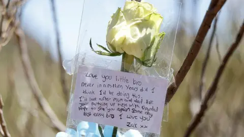 Reuters A white rose with a message saying 'Love you little bro'