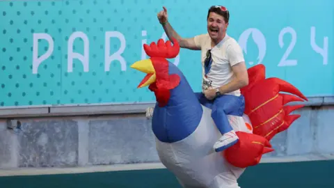 Getty Images A man wears a costume that appears to show him riding atop an inflatable cockerel