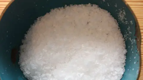 A blue dish full of white sea salt crystals