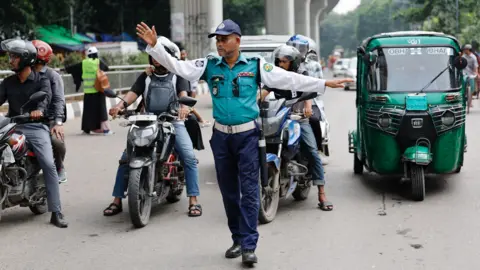 Reuters A traffic police officer gestures to the vehicles at an intersection in Dhaka