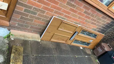 Natalie Gerrard Natalie Gerrard's broken front door lies on its side outside after it was smashed in by police officers with a battering ram