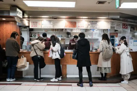 Getty Images Customers order takoyaki at a store in Osaka, Japan in 2023