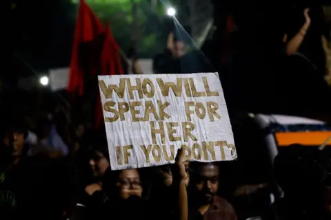 Reuters A woman holds a placard as she attends a candlelight vigil held outside Jadavpur University campus, condemning the rape and murder of a trainee medic at a government-run hospital in Kolkata, Ind