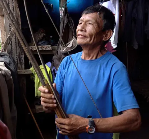 Juan wearing a blue T-shirt, holding a bow 