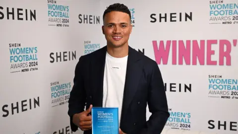 Getty Images Jermaine Jenas smiling and holding up an award at the Women's Football Awards