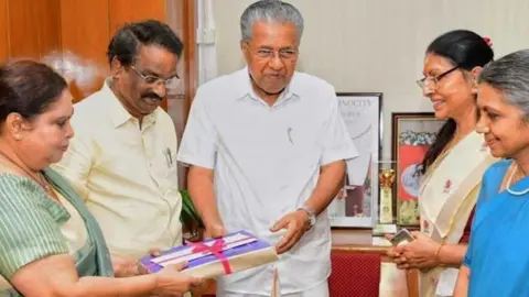 Chief Minister's Office Members of the commission seen handing over a report tied up with pink ribbon to Kerala Chief Minister Pinarayi Vijayan