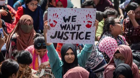 Getty Images Protesters hold placards during the demonstration outside the High Court building demanding justice for the victims arrested and killed in the recent countrywide violence