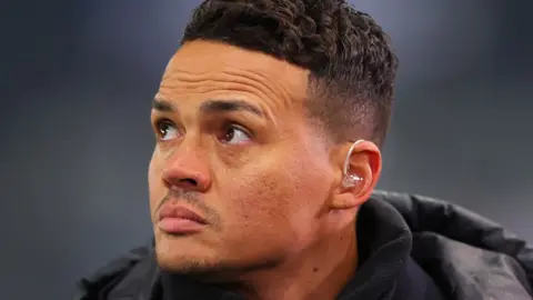 Getty Images Jermaine Jenas wearing a coat and looking impassively off camera