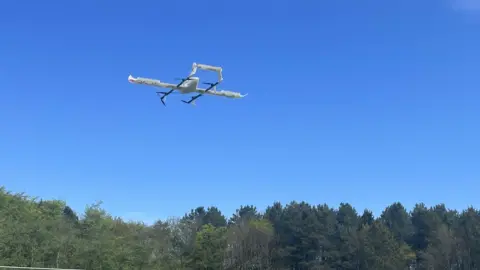 Apian Ltd/PA Wire A drone comes in to land in a field with trees in the background. 