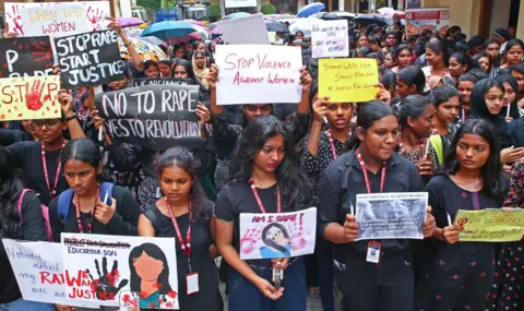 Arun Chandra Bose/BBC A large group of women wearing black tops holds up placards during a protest on violence against women