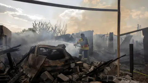 Reuters An emergency worker extinguishes a fire that destroyed a private house after a Russian strike on a residential area in Pokrovsk