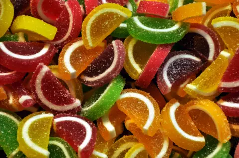 Victor Tregubov Candied sweets shaped like citrus segments of various colours on sale in a market