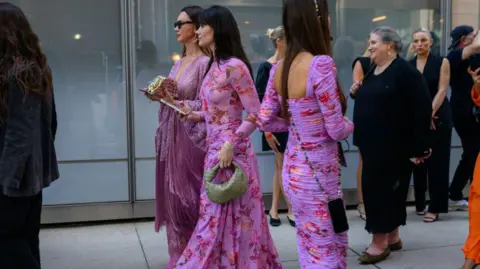 Getty Images Women outside Pat Bo's New York show wearing pink and purple floral dresses 