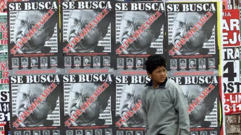 AFP A boy passes "Wanted" posters in Lima calling for the extradition of former Peruvian President Alberto Fujimori 30 July, 2003