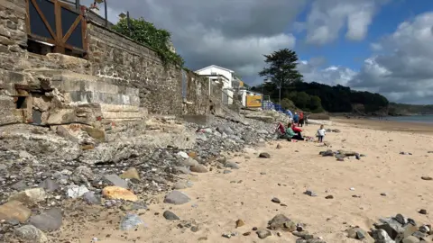 Saundersfoot beach, complete with pebbles in the foreground and people in the background 