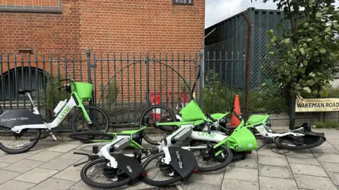 Brent Council Four out of a group of five dockless e-bikes operated by Lime are laying on their sides with poor parking like this are among the reasons Brent Council has threatened to ban them from the borough 