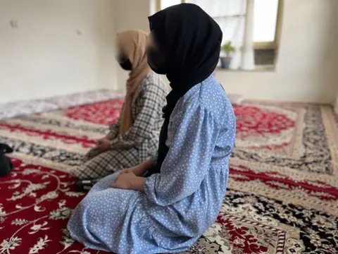 Two Afghan school girls sit on the floor